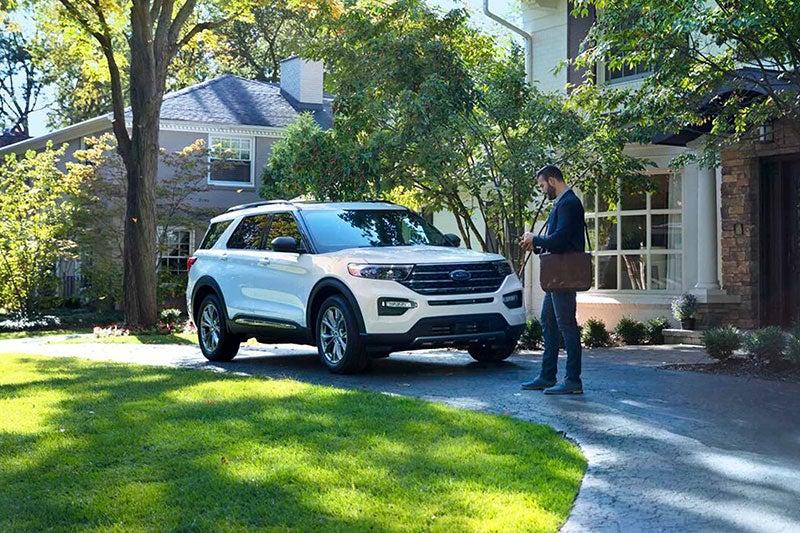 Exterior shot of man in front of house with a white Explorer® SUV cell phone in hand